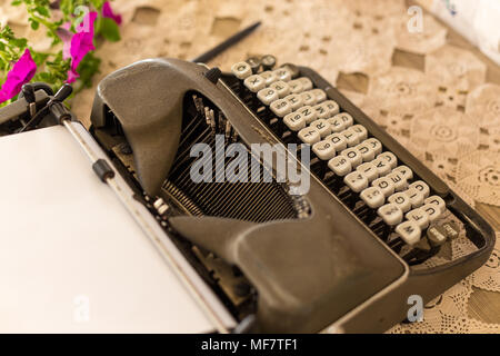 Writing concept. Gray retro typewriter with white keys placed on lace tabletop. Shot with shallow depth of field. Stock Photo