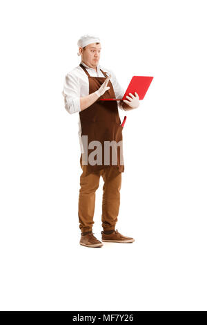 Surprised butcher posing with a laptop isolated on white background Stock Photo