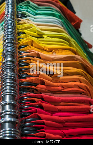 Male men’s shirts sorted in color order on hangers on a shop wardrobe closet rail Stock Photo
