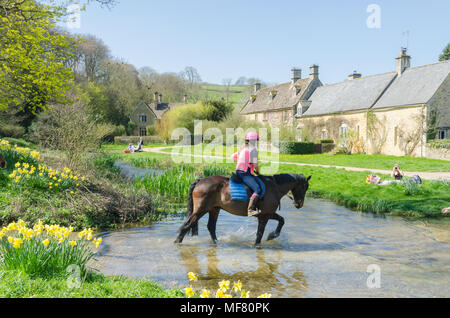 Horse trotting through River Eye in the pretty Cotswold village of Upper Slaughter in Gloucestershire,UK Stock Photo