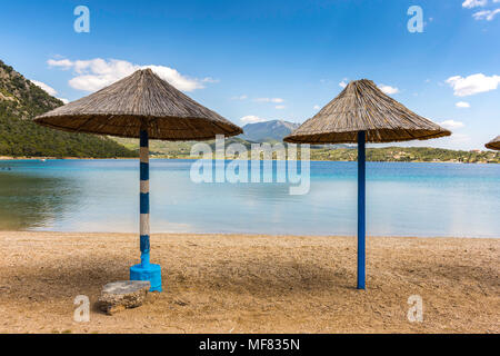 Straw parasols on the sandy beach in Greece Stock Photo