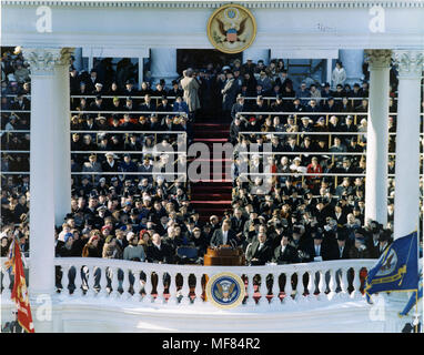 PX65-108:CC18209  20 January 1961  President John F. Kennedy delivers his inaugural address.  Photograph includes: President John F. Kennedy, First Lady Jacqueline Kennedy, Rose Kennedy (far left) Joseph P. Kennedy, Sr., President Dwight Eisenhower, Vice President Lyndon B. Johnson, Richard Nixon, President Truman, and several others seated behind the president.  North Portico, Capitol Building, Washington D.C.  Please credit: 'CWO Donald Mingfield, US Army Signal Corps/John F. Kennedy Presidential Library and Museum, Boston' Stock Photo