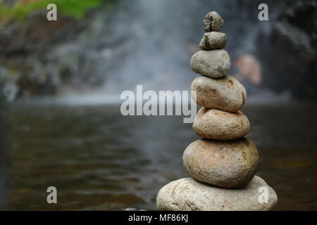 Pebble on the waterfall. The royalty high quality free stock of stones pyramid on pebble waterfall symbolizing stability, zen, harmony, balance Stock Photo
