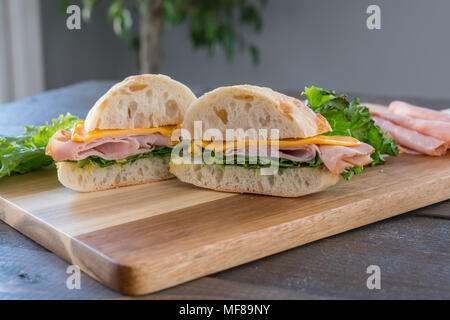 Sliced Ham and Cheese Sandwich on ciabatta roll on Cutting Board Stock Photo