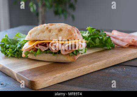 Sliced Ham and Cheese Sandwich on ciabatta roll on Cutting Board Stock Photo