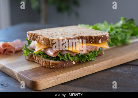 Fresh Ham and Cheese Sandwich on Whole Wheat Bread on Cutting Board Stock Photo