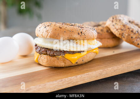 Sausage, egg and cheese breakfast sandwich with an everything bagel on cutting board Stock Photo