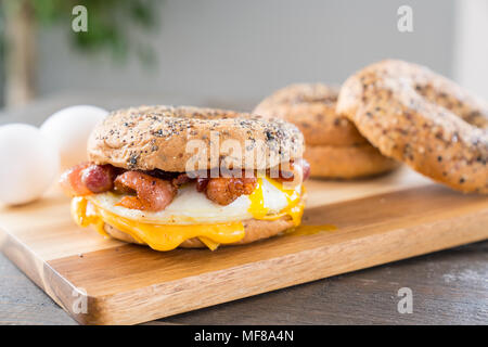 Bacon, egg and cheese breakfast sandwich with an everything bagel on cutting board Stock Photo