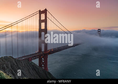 Fog drifts through San Francisco Bay over the Golden Gate Bridge at sunrise Stock Photo
