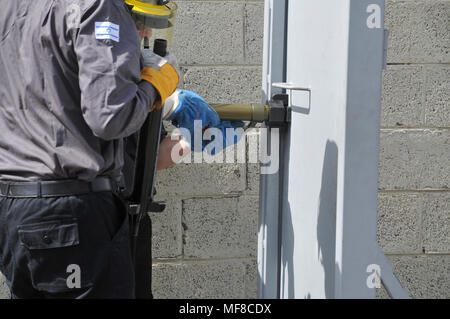 Fire fighter uses hydraulic tools to breach a locked door Stock Photo