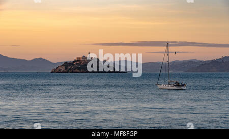 A sailboat goes by Alcatraz Island in San Francisco Bay at dusk Stock Photo