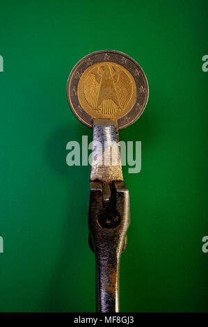 coin of two euros, clamped in a clamp, the concept of a financial crisis,