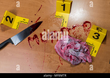 The word “murder” written in blood on a wood surface beside a bloody knife and a bloody rag, all marked by crime scene evidence markers.