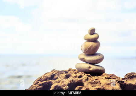 Stones balance and wellness retro spa concept, inspiration, zen-like and well being tranquil composition. Close-up of white pebbles stack over blue se Stock Photo