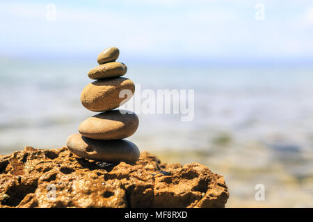 Stones balance and wellness retro spa concept, inspiration, zen-like and well being tranquil composition. Close-up of white pebbles stack over blue se Stock Photo