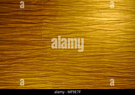 Close-up view of paper lamp wrinkled vellum texture, switched on with warm light. Background. Stock Photo