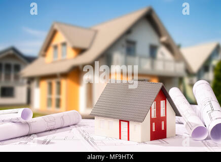 Blueprints and architectural model with a new building in the background Stock Photo