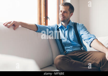 Man sitting and relaxin on sofa at home Stock Photo
