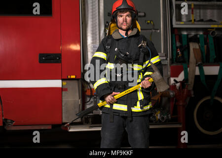 handsome young fireman holding fire hose in uniform Stock Photo