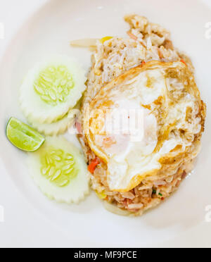 selective focus close up traditional Thai Asian cuisine food menu: delicious Thai fermented pork fried rice with fried egg on top garnished with lemon Stock Photo