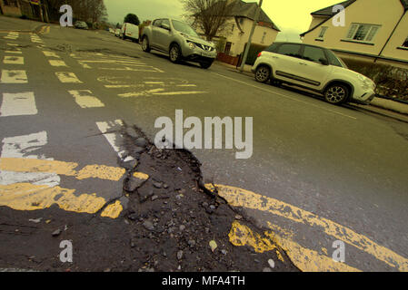 pot holes damaged road  car cars on street with  double yellow lines no entry markings Stock Photo