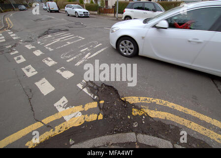 pot holes damaged road  car cars on street with  double yellow lines no entry markings Stock Photo