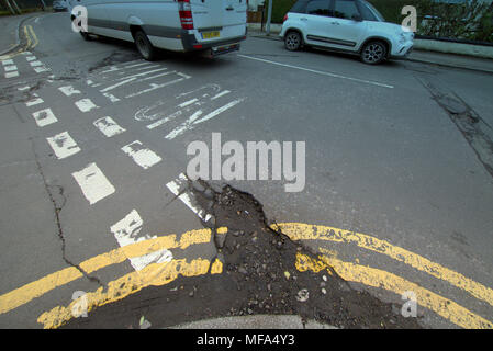 pot holes damaged road  car cars on street with  double yellow lines no entry markings Stock Photo