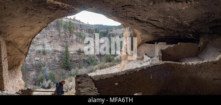 Man exploring cave dwelling  at Gila Cliff Dwellings National Monument, Silver City New Mexico, panorama Stock Photo