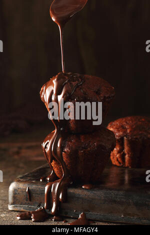 melted chocolate pouring on chocolate-banana muffins with walnuts, photographed with one flash and one silver reflector Stock Photo