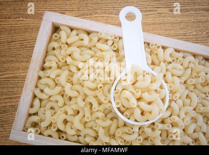 Food and Cuisine, Uncooked and Dried Elbow Macaroni or Gomiti Pasta in Plastic Measuring Cup. Stock Photo