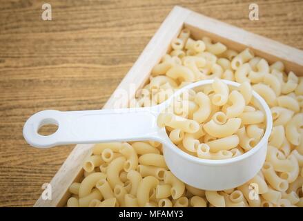 Food and Cuisine, Uncooked and Dried Elbow Macaroni or Gomiti Pasta in Plastic Measuring Cup. Stock Photo