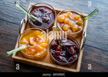 Various glass bowl of Fruit jams Apricot, cherry, strawberry, damson plum in wooden tray. breakfats concept. Stock Photo