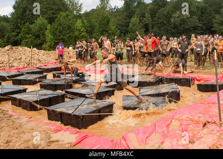 Competitors struggle to maintain their balance running across floating plaforms at the Rugged Maniac event on August 22, 2015 in Conyers, GA. Stock Photo
