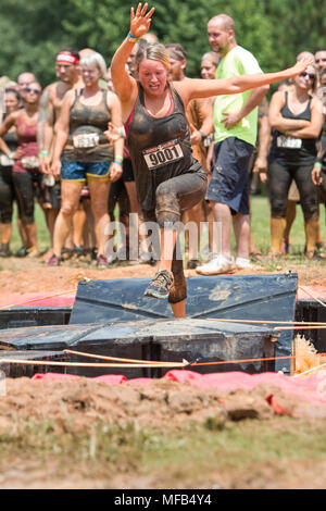 A young woman tries to run across platforms floating in a pit of muddy water at the Rugged Maniac Obstacle Course on August 22, 2015 in Conyers, GA. Stock Photo