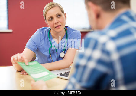 Female Doctor Discussing Leaflet With Male Patient Stock Photo