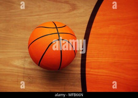 Basketball ball laying on hardwood court floor, top view Stock Photo