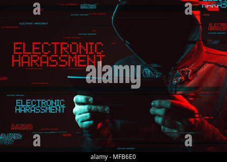 Electronic harassment concept with faceless hooded male person using tablet computer, low key red and blue lit image and digital glitch effect Stock Photo