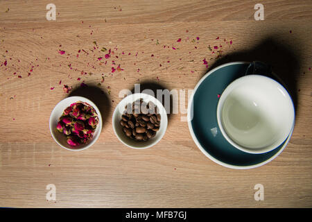 Flower buds and coffee beans with dishes up view. Rose raf coffee ingredients on table. Stock Photo