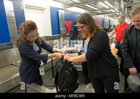 Airline ticket agent puts tag on passengers luggage. Minneapolis St Paul International Airport - Lindbergh Terminal Minneapolis Minnesota MN USA Stock Photo