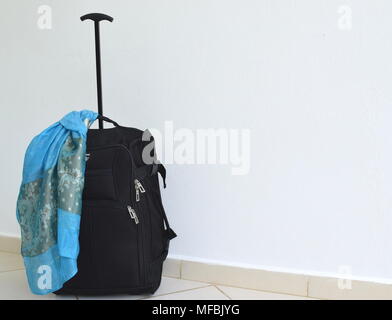 Black suitcase with a beautiful silk scarf on white textured background Stock Photo