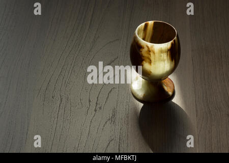 A glass of onyx stone stands on a table lit by a sunbeam Stock Photo