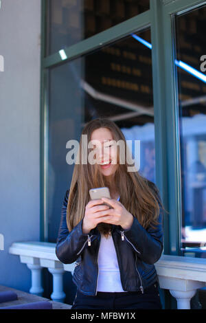 Young female person typing by smartphone at street cafe. Stock Photo