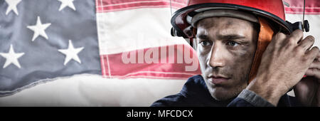 Composite image of serious fireman putting on helmet Stock Photo