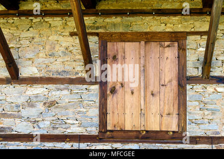 Closed wooden shutters on wall made of stone blocks and wooden timbers, rustic background Stock Photo