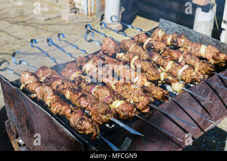Marinated barbecue meat on skewer. Shish kebab or Shashlyk meaning skewered  meat. Beef or pork on grill on an open fire with smoke. Street food, picnic  concept Stock Photo