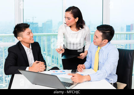 Asian banker counseling man in office Stock Photo