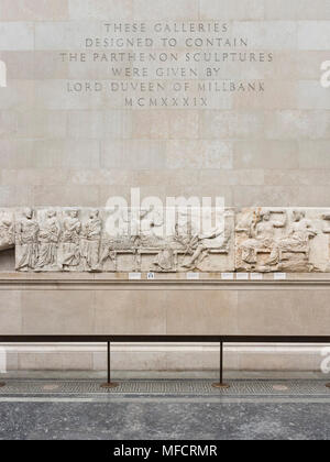 London. England. British Museum, person looking at the Parthenon Frieze (Elgin Marbles), Four Olympian gods seated on stools (central panel), from the Stock Photo