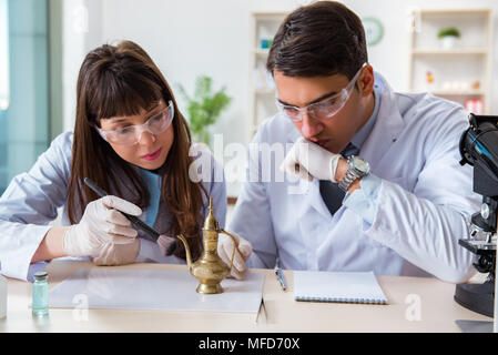 Two archeologists looking at ancient gold lamp Stock Photo