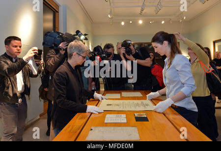 25 April 2018, Germany, Trier: Surrounded by journalists, curator Barbara Wagner (L) and restorator Sarah Bruch place the doctoral certificate of Karl Marx on the exhibition table at the large Karl Marx exhibition at the Rheinische Landesmuseum Trier. According to its organizers, Rhineland-Palatinate's state exhibition 'Karl Marx 1818 - 1883. Life. Work. Times' is the first ever historico-cultural exhibition on the thinker. It can be seen at the Rheinische Landesmuseum Trier and at the Simeonstift Trier city museum. Photo: Harald Tittel/dpa Stock Photo