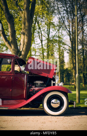 Red Vintage Ford pickup truck sits with bonnet open showing engine, side on portrait, with chrome wheel hubs Stock Photo
